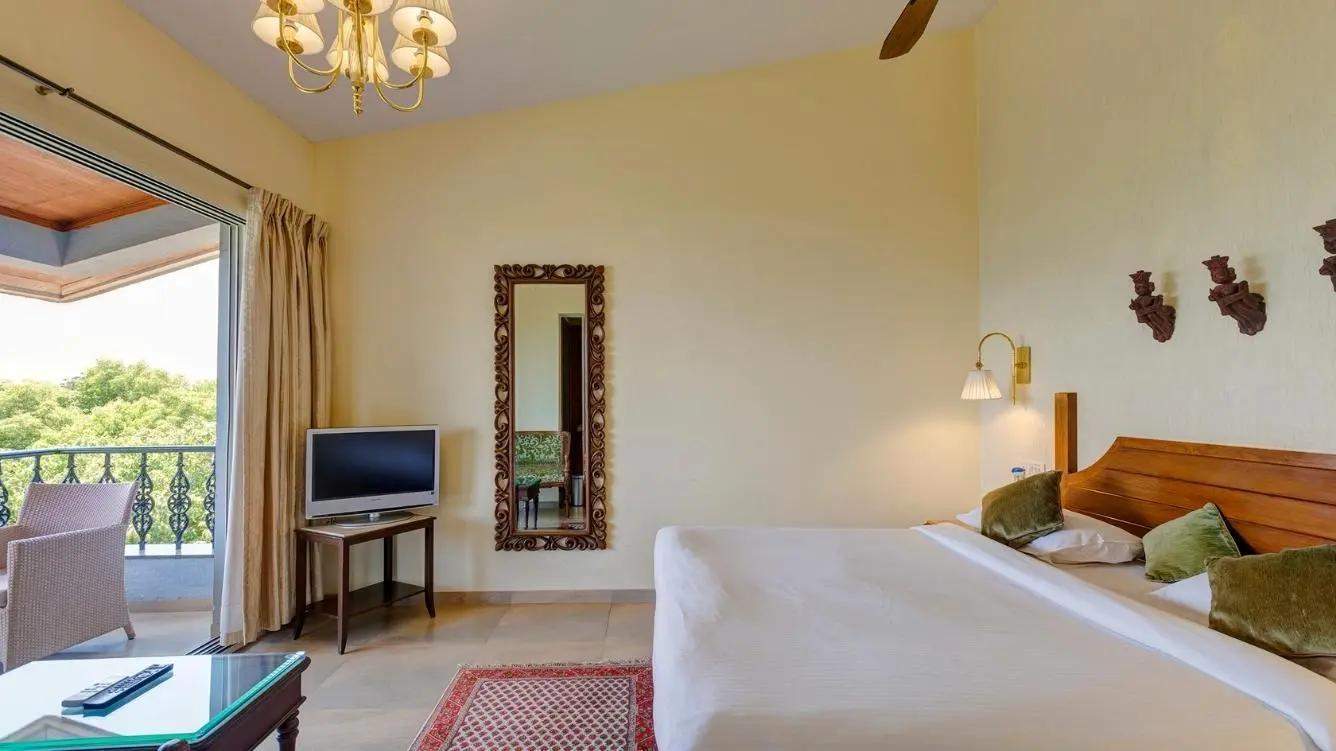 Elegant garden view deluxe room with comfortable bed, private balcony and scenic tree views at Ramsukh Resort in Mahabaleshwar